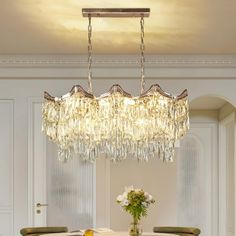 a chandelier hanging from the ceiling in a dining room with chairs and table