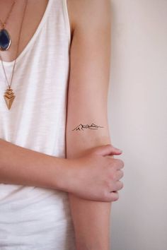 a woman's arm with a tattoo on it that says mountains and a heart