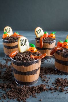 three halloween desserts in plastic cups with dirt on the ground