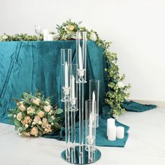 a tall glass candle holder sitting on top of a table next to a flower arrangement