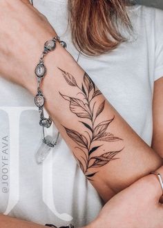 a woman's arm with a leaf tattoo on the left side of her arm