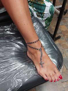 a woman's foot with a cross on it and a beaded ankle bracelet