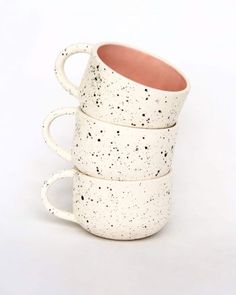 four speckled coffee mugs stacked on top of each other with one cup in the middle