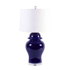 a blue glass table lamp with a white shade on the top and bottom part of it