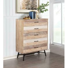 a wooden dresser with drawers in front of a painting on the wall next to a window