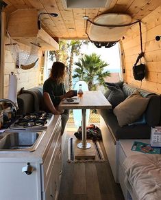 a woman sitting at a table in the back of a camper