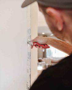 a man holding a pair of scissors in front of a wall with white paint on it