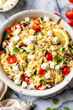 a white bowl filled with pasta salad and topped with feta cheese