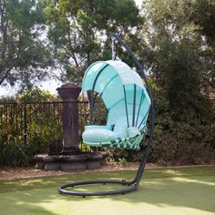 a swing chair in the middle of a lawn with trees and bushes behind it,