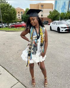 a woman in a graduation cap and gown is standing on the street with her hand on her hip