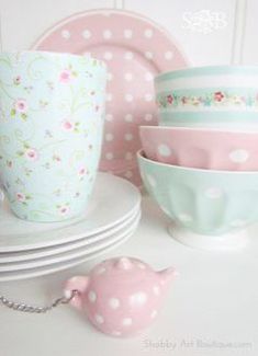 pink and white polka dot cups, saucers, and plates on a table with a bird figurine next to them