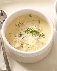 there is a bowl of soup on the plate with spoons and fork next to it