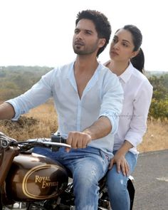 a man and woman riding on the back of a motorcycle