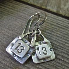 two silver dice earrings with numbers on them