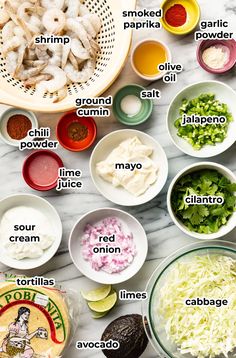 the ingredients for shrimp salad laid out on a white marble counter top with names in spanish