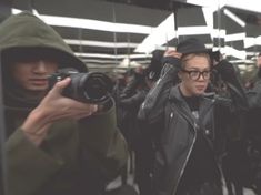 a man taking a selfie in front of a mirror with his camera and other people behind him