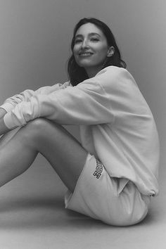 a black and white photo of a woman sitting on the floor with her legs crossed