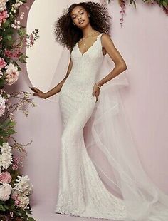 a woman in a white wedding dress standing next to a floral arch with flowers on it