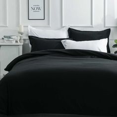 black and white bedding in a bedroom with pictures on the wall behind it that says now