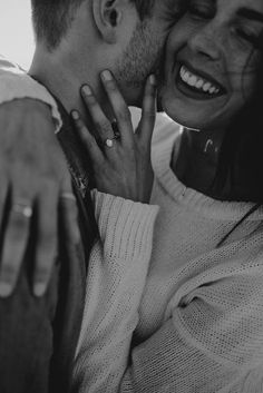 black and white photograph of a couple embracing each other with rings on their fingers in front of the camera