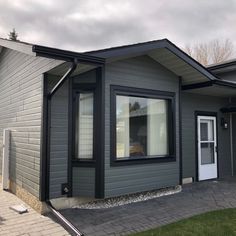 a gray house with black trim and windows on the front door is seen in this image