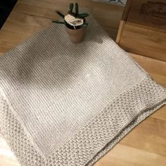 a potted plant sitting on top of a wooden table next to a knitted blanket