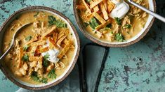 two bowls filled with chicken and tortilla soup on top of a blue table