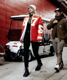 a man and woman walking next to each other in front of a red building with a golf cart