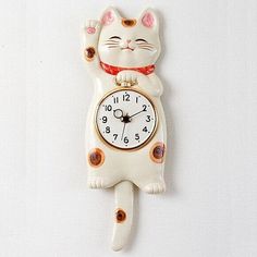 a white cat clock hanging on the wall with its paws in the air and it's eyes closed