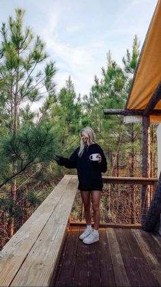 a woman standing on a deck with trees in the background