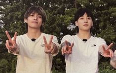 two young men standing next to each other with their hands in the shape of peace signs