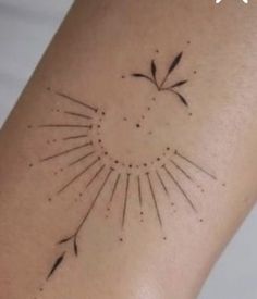 a small sun tattoo on the back of a woman's arm, with black ink