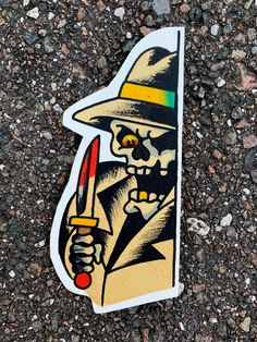 a sticker with a skeleton holding a knife and wearing a hat on the ground