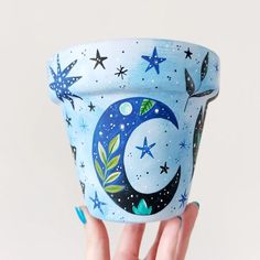 a hand holding up a blue cup with stars and moon painted on it