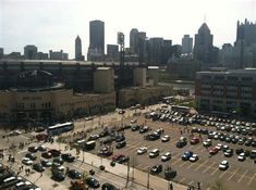 an aerial view of a parking lot with cars parked in it and buildings in the background