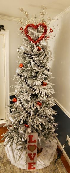 a white christmas tree decorated with red and silver ornaments, bows, and heart decorations