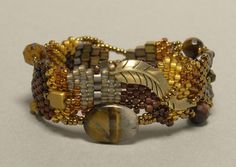 a close up of a bracelet on a white surface with gold and brown beads around it