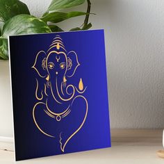 a blue and gold ganeshi card sitting on a table next to a potted plant