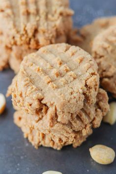 three peanut butter cookies stacked on top of each other with peanuts scattered around the edges