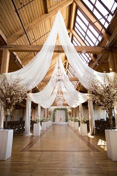 an indoor wedding venue with white draping and flowers