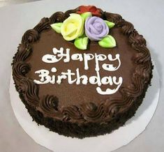 a birthday cake with chocolate frosting and colorful flowers on top that says happy birthday