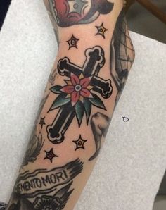 a woman's arm with tattoos on it and a cross in the middle, surrounded by stars