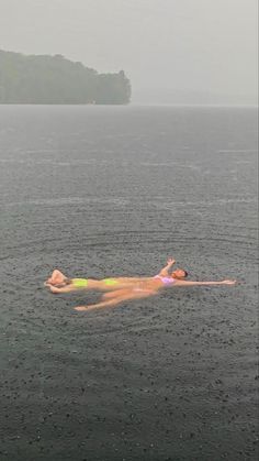 a person floating in the water on top of a body of water with an island in the background