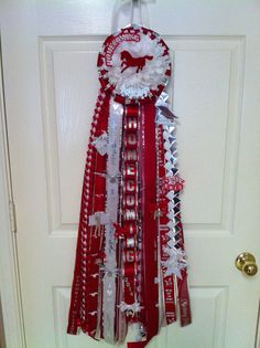 a door hanger decorated with ribbons and ribbon clips for the holiday season, hanging on a white door