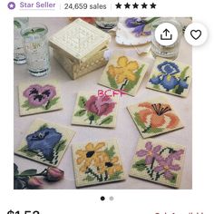 cross stitch coasters with flowers on them sitting on a table next to water glasses