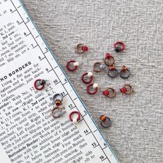 several pairs of red and black earrings sitting on top of a piece of paper