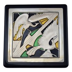 two white birds flying in the sky with green and yellow accents on it's wings