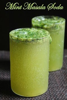 two glasses filled with green liquid on top of a table