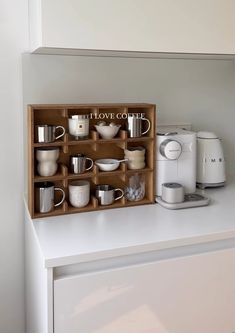 a wooden box with cups and coffee mugs in it sitting on top of a counter