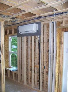 an air conditioner mounted to the side of a wall in a room under construction